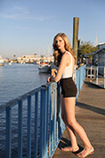 fashion model in white swimsuit on boardwalk by water